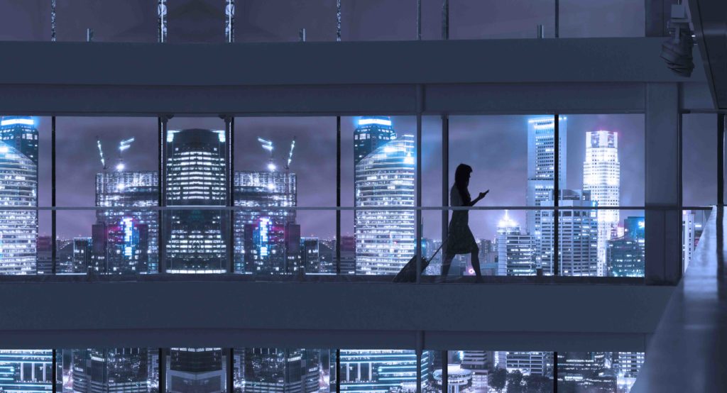 Young woman using smartphone and pulling suitcase, city skyline in view